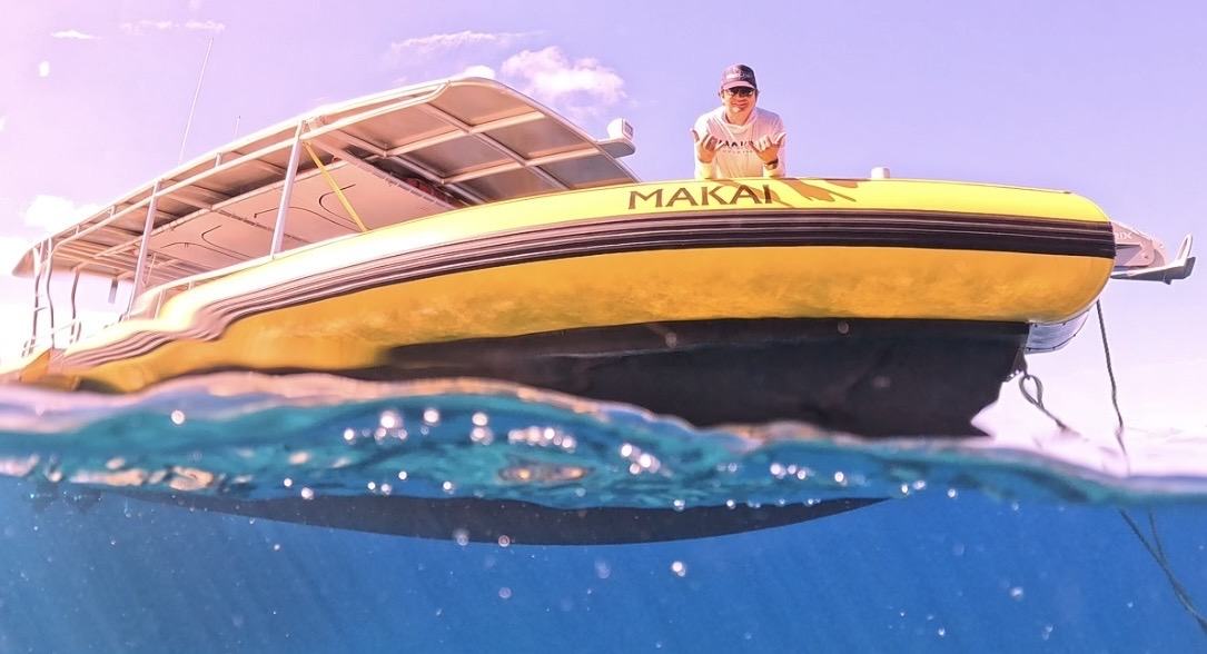 MAKAI at anchor in clear water with a crew member on the bow